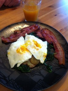 Eggs on a bed of sauteed baby potato & kale, topped with eggs and served w/ BACON.